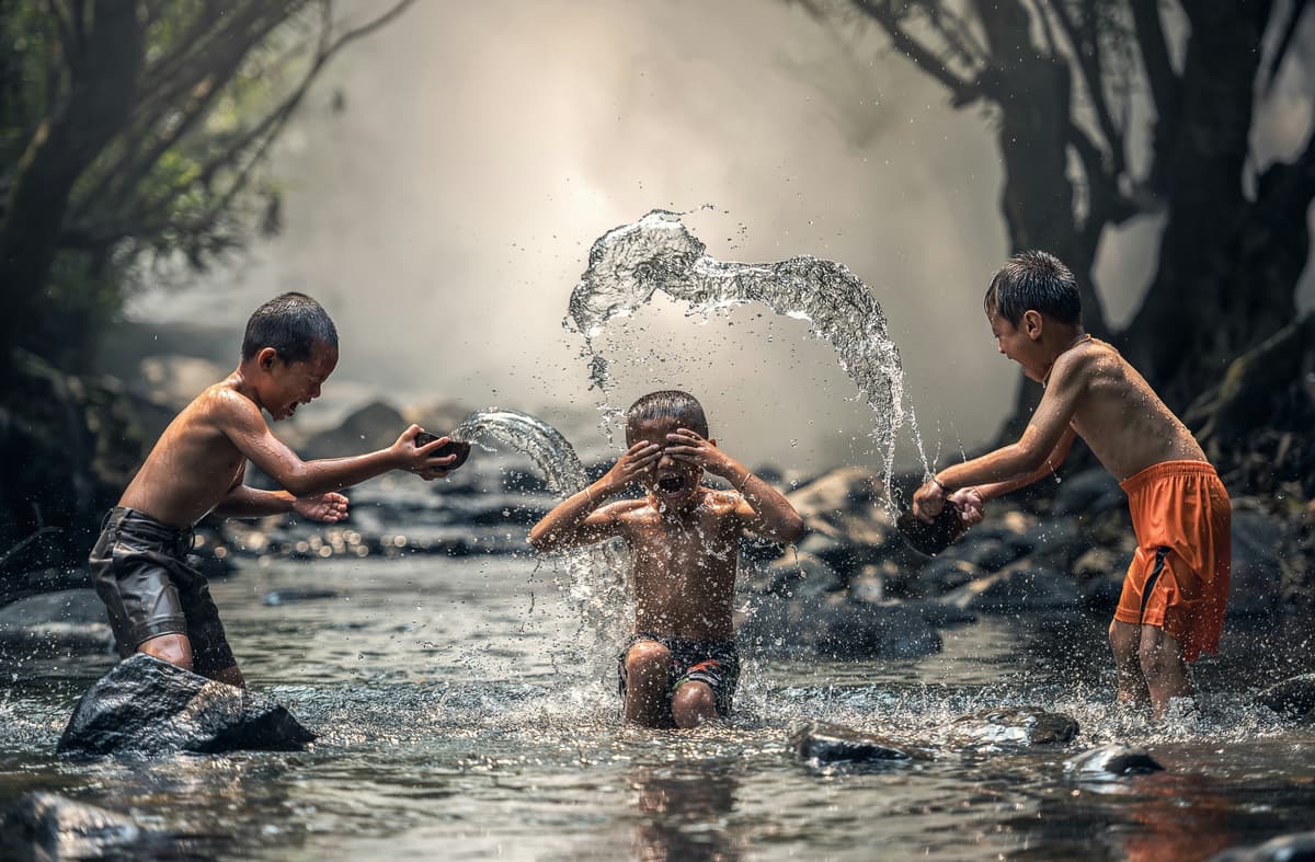 Children playing and splashing water in a forest stream